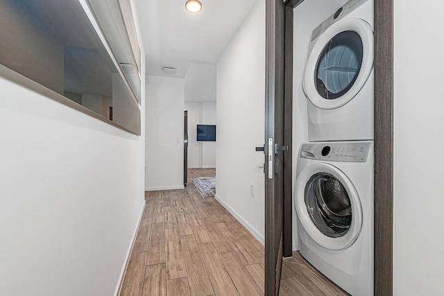 washroom with light hardwood / wood-style floors and stacked washer and dryer