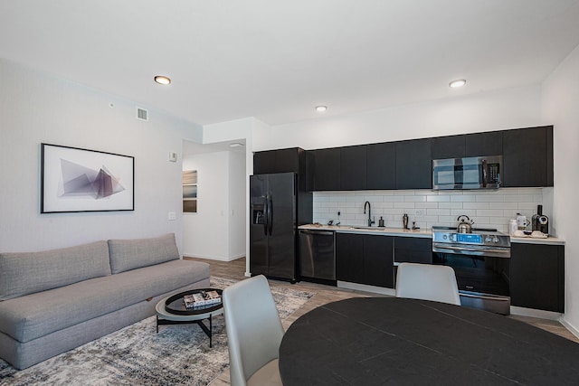 kitchen with decorative backsplash, stainless steel appliances, light hardwood / wood-style floors, and sink