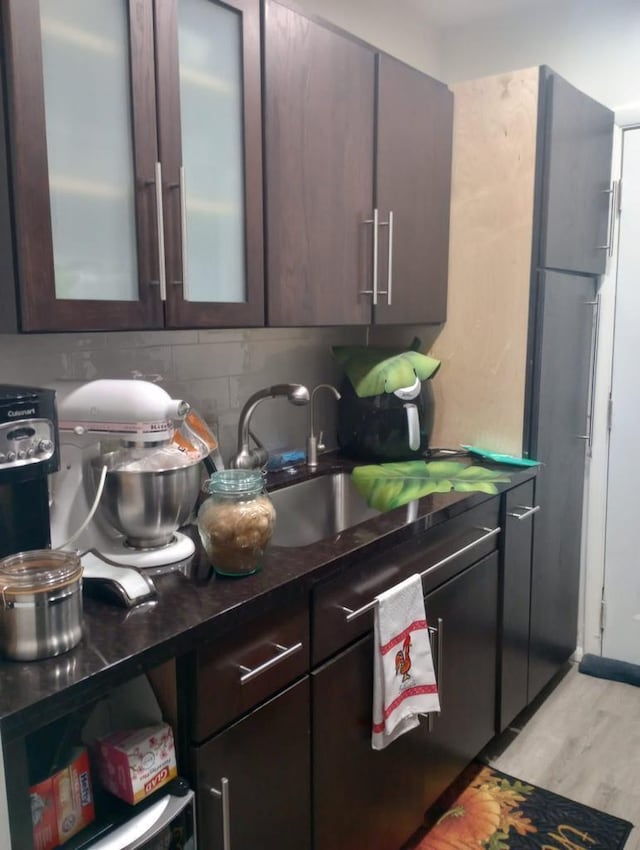 kitchen with dark brown cabinets, light hardwood / wood-style flooring, and sink