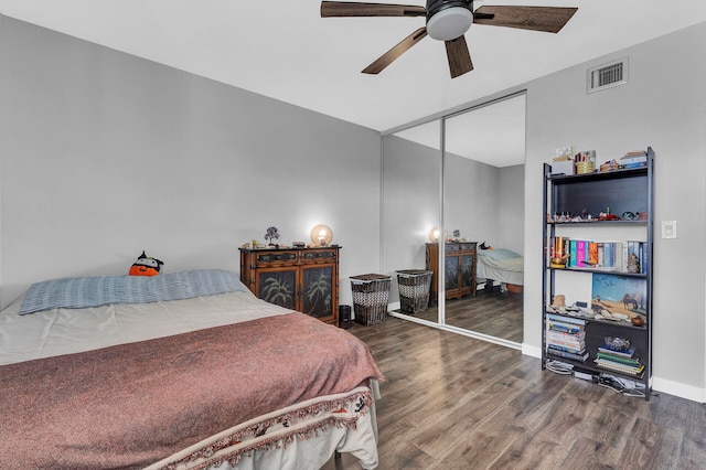 bedroom with ceiling fan, dark wood-type flooring, and a closet