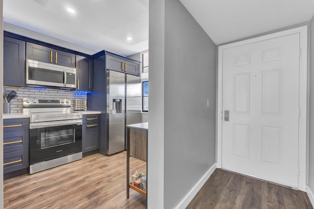 kitchen featuring blue cabinetry, decorative backsplash, dark hardwood / wood-style flooring, and appliances with stainless steel finishes