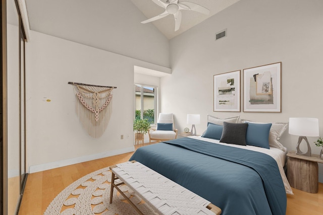 bedroom with ceiling fan, a closet, high vaulted ceiling, and light wood-type flooring