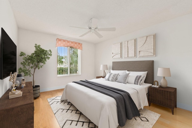 bedroom featuring ceiling fan, a textured ceiling, and light hardwood / wood-style flooring