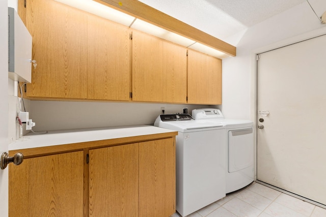 washroom featuring cabinets, light tile patterned floors, washing machine and dryer, and a textured ceiling