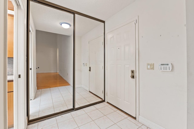 hallway featuring light tile patterned flooring and a textured ceiling