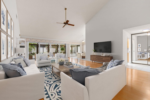 living room with ceiling fan, high vaulted ceiling, and light wood-type flooring