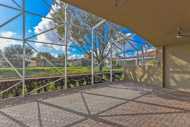 view of patio featuring a ceiling fan, a residential view, and glass enclosure