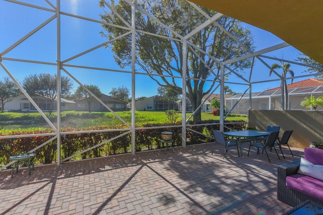 view of patio / terrace with glass enclosure, outdoor dining space, and a residential view