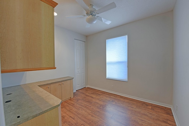 empty room featuring a ceiling fan, baseboards, and light wood finished floors