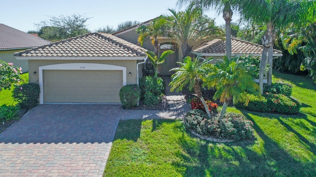 mediterranean / spanish-style house with a garage, a tiled roof, decorative driveway, stucco siding, and a front lawn