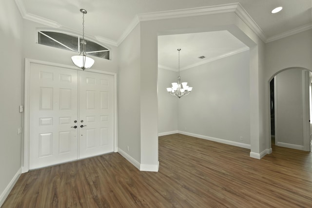 entrance foyer with ornamental molding, arched walkways, dark wood finished floors, and baseboards