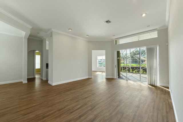 spare room with arched walkways, visible vents, ornamental molding, wood finished floors, and baseboards