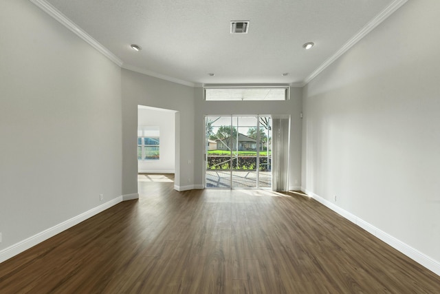 spare room featuring dark wood-type flooring, visible vents, crown molding, and baseboards