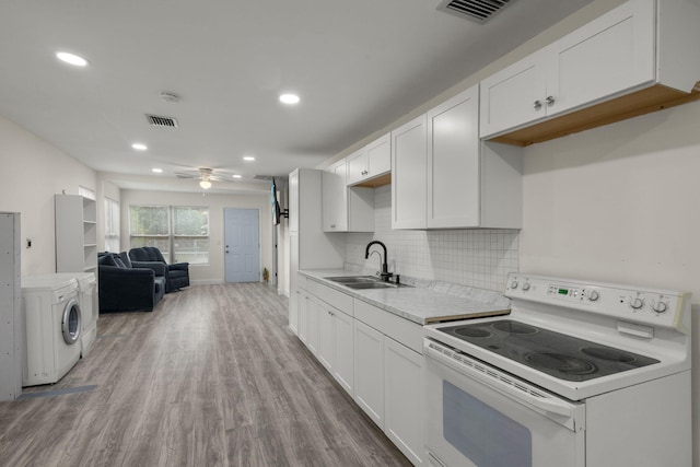 kitchen with white range with electric cooktop, sink, washer and dryer, light wood-type flooring, and white cabinetry