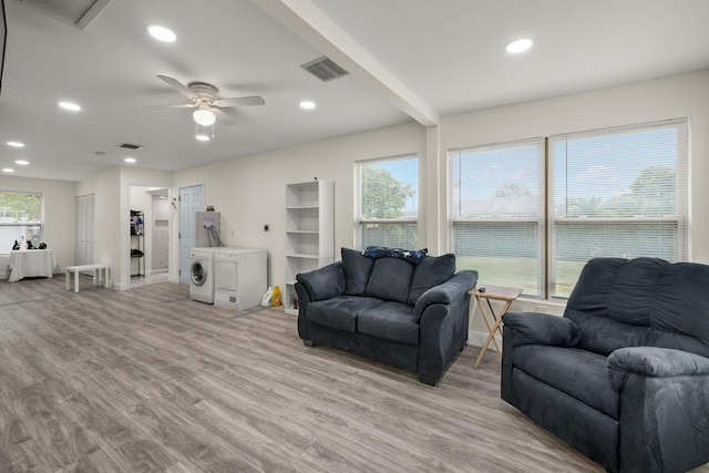 living room featuring independent washer and dryer, light wood-type flooring, a wealth of natural light, and ceiling fan