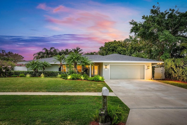 ranch-style house with a garage and a yard