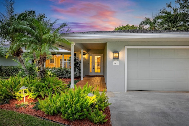 exterior entry at dusk featuring french doors and a garage