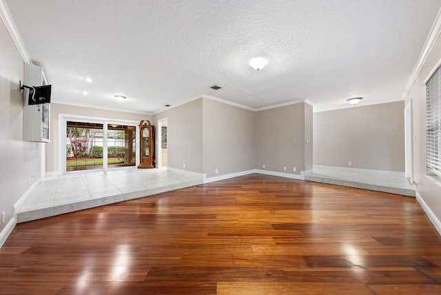 unfurnished living room featuring wood-type flooring, a textured ceiling, and ornamental molding