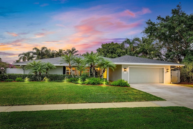 single story home with a garage and a lawn