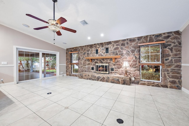 unfurnished living room featuring lofted ceiling, a stone fireplace, crown molding, ceiling fan, and light tile patterned floors