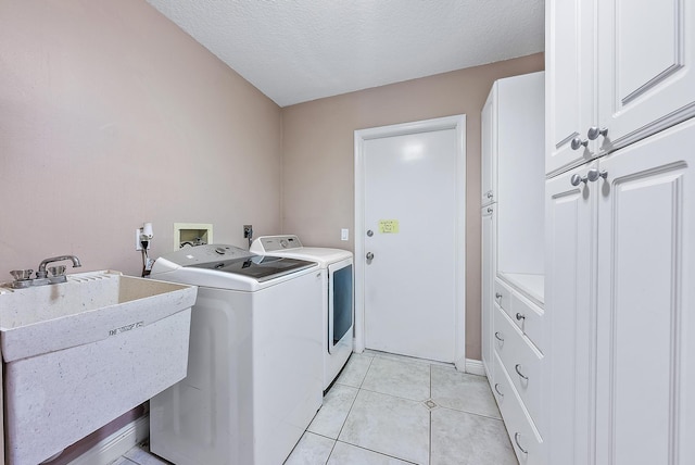 washroom with sink, light tile patterned floors, cabinets, a textured ceiling, and separate washer and dryer