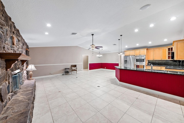 kitchen with ceiling fan, stainless steel appliances, backsplash, lofted ceiling, and a fireplace