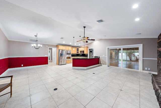 kitchen with lofted ceiling, decorative light fixtures, ornamental molding, stainless steel appliances, and ceiling fan with notable chandelier