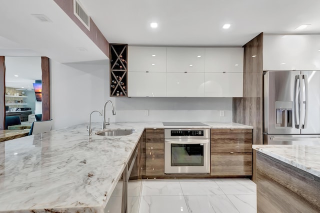 kitchen featuring light stone counters, sink, white cabinets, and appliances with stainless steel finishes