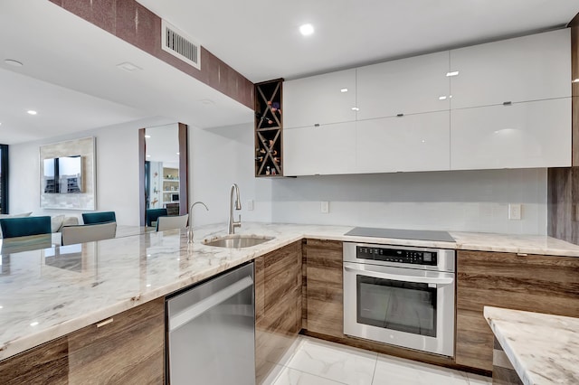 kitchen with light stone counters, white cabinetry, sink, and appliances with stainless steel finishes