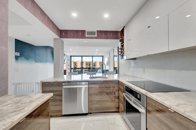 kitchen featuring white cabinetry, sink, backsplash, oven, and black electric cooktop