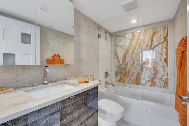 full bathroom with vanity, toilet, tile walls, and tiled shower / bath