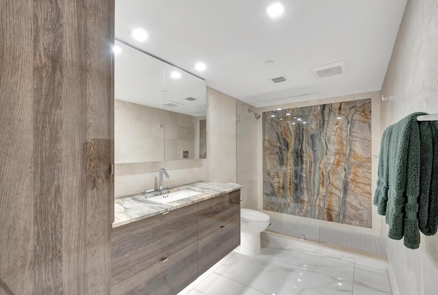 bathroom with vanity, toilet, tile walls, and a shower with shower door