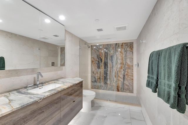 bathroom with tiled shower, vanity, and toilet