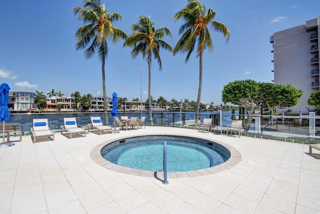 view of swimming pool with a patio, a water view, and a hot tub