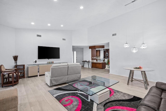 living room featuring high vaulted ceiling and light hardwood / wood-style floors