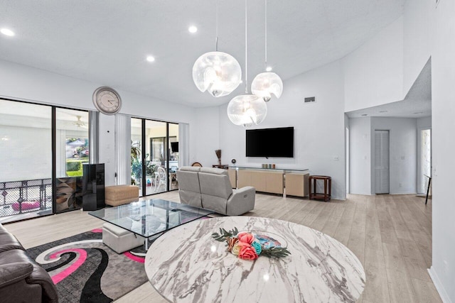 living room with light hardwood / wood-style flooring, high vaulted ceiling, and a textured ceiling