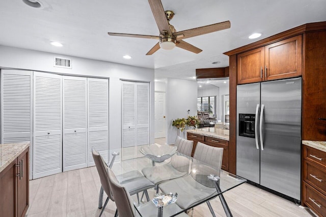 kitchen featuring ceiling fan, light hardwood / wood-style floors, light stone countertops, and stainless steel refrigerator with ice dispenser