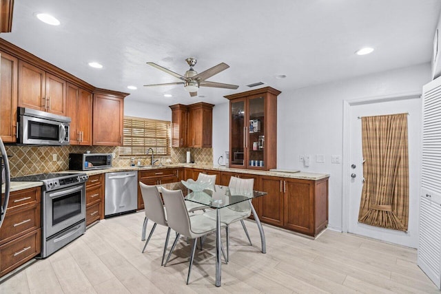 kitchen with ceiling fan, sink, stainless steel appliances, and light hardwood / wood-style flooring