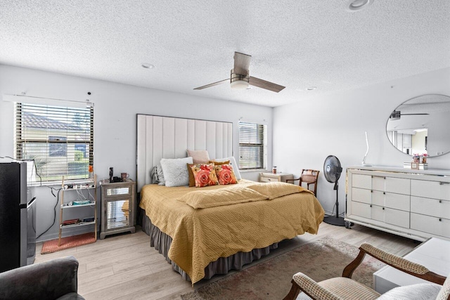 bedroom featuring a textured ceiling, light wood-type flooring, and ceiling fan