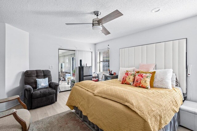 bedroom with ceiling fan, light hardwood / wood-style floors, a textured ceiling, and a closet