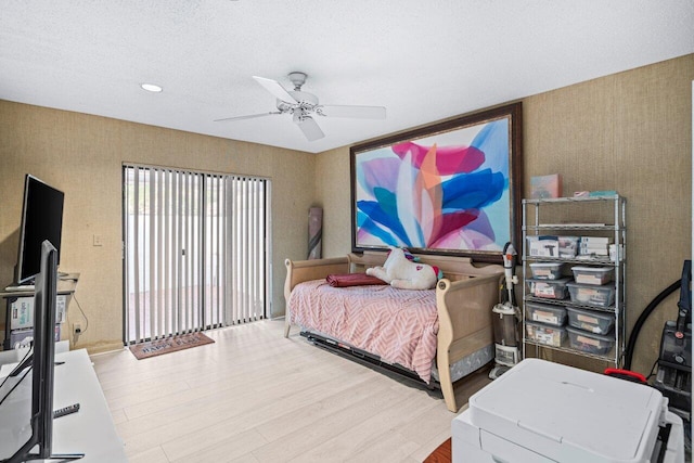 bedroom featuring ceiling fan, hardwood / wood-style floors, and a textured ceiling