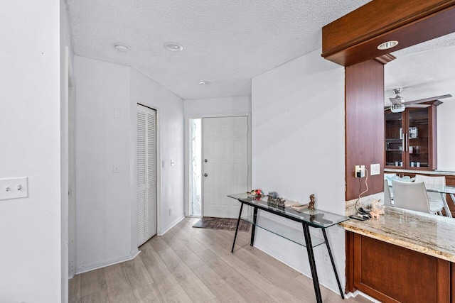 hall featuring a textured ceiling and light wood-type flooring