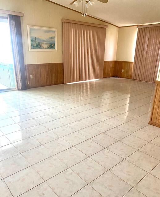 unfurnished room featuring ceiling fan, lofted ceiling, and wood walls