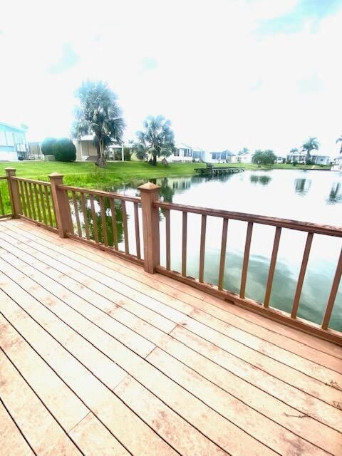 wooden terrace featuring a lawn and a water view