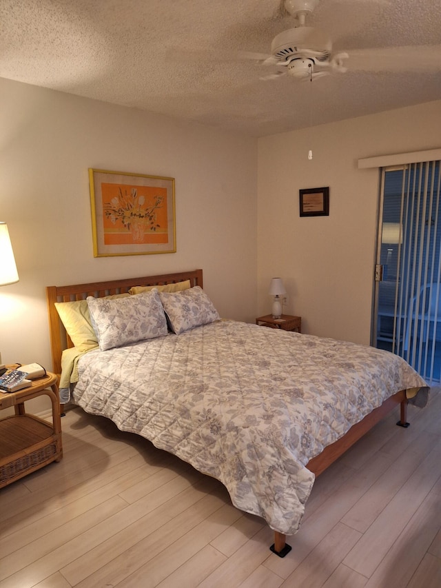 bedroom with ceiling fan, wood-type flooring, and a textured ceiling