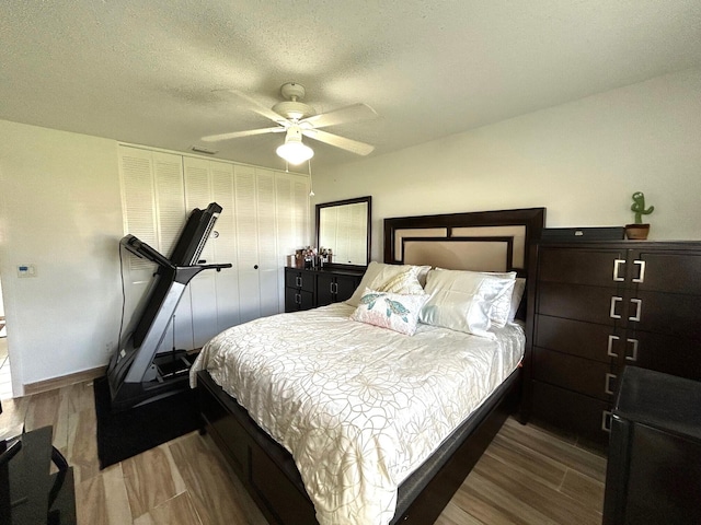 bedroom with hardwood / wood-style flooring, ceiling fan, and a textured ceiling