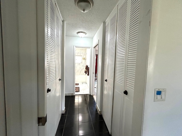 2522 Emory Dr E Unit I, West Palm Beach, FL 33415 - corridor featuring a textured ceiling, dark tile patterned flooring, and baseboards