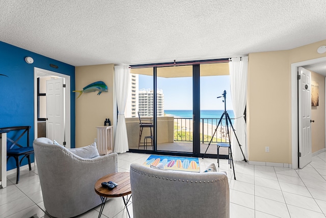 living room featuring floor to ceiling windows, light tile patterned floors, a water view, and a textured ceiling