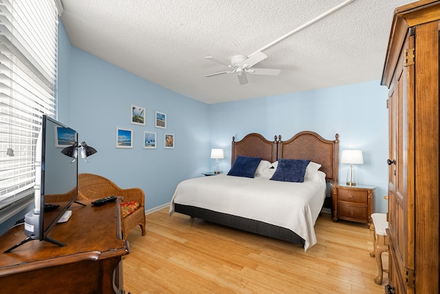 bedroom with a textured ceiling, light hardwood / wood-style floors, and ceiling fan