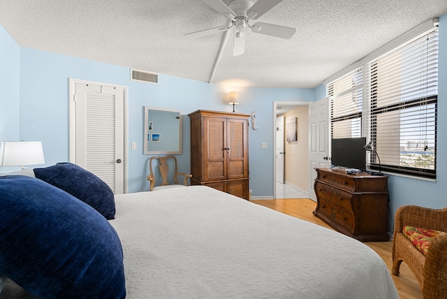 bedroom featuring ceiling fan, light wood-type flooring, a textured ceiling, and a closet